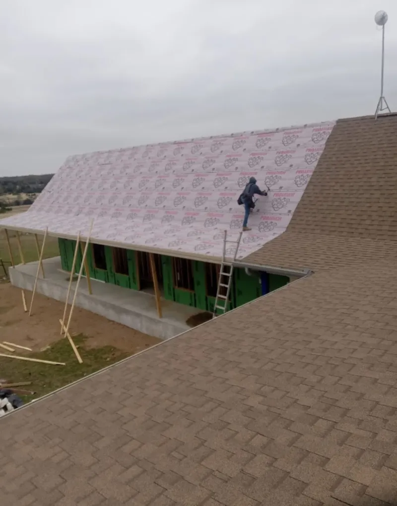 Worker preparing underlayment for a metal roof installation in St. Stephens